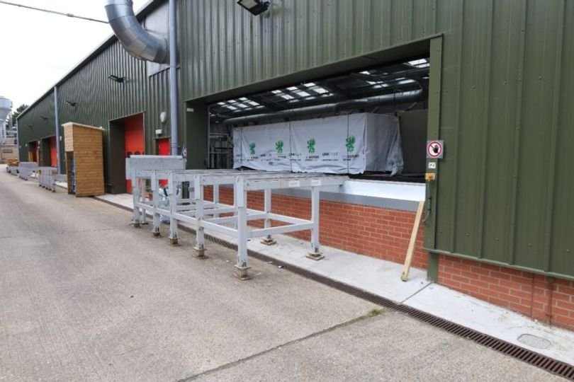 A conveyor belt in a warehouse with a warning sign in the foreground, highlighting the importance of workplace safety and accident prevention in relation to conveyor accidents