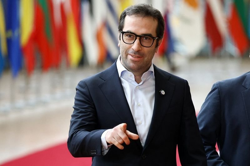 A Spanish air traffic control tower, with a US military plane in the background, highlighting the country's decision to close its airspace to US planes involved in the Iran war, a significant development in international relations and conflict resolution