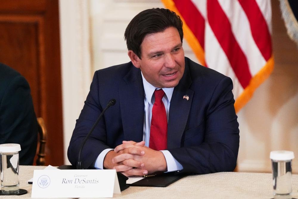 Florida Governor Ron DeSantis signing the proof of citizenship bill, surrounded by supporters, with a focus on voting laws and electoral reform