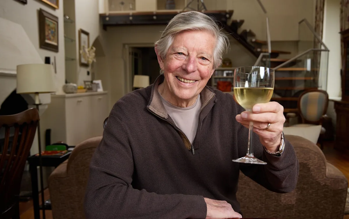 An 80-year-old woman laughing and chatting with friends at a social gathering, surrounded by colourful balloons and a warm atmosphere, highlighting the importance of socialising in the golden years