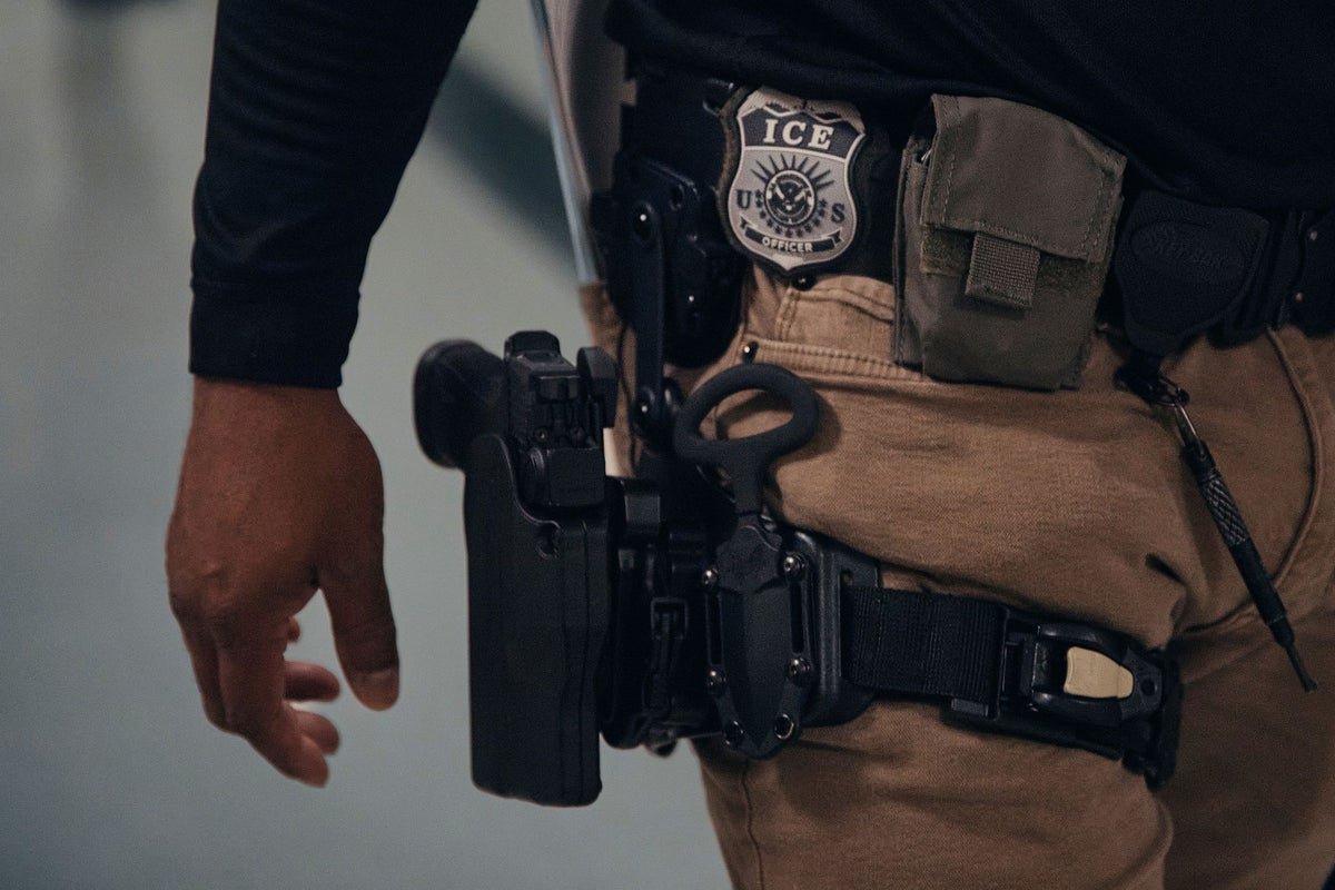 A photograph of a military base with a couple in the foreground, highlighting the challenges faced by military families affected by immigration laws, with a focus on the Army sergeant's wife arrested by ICE