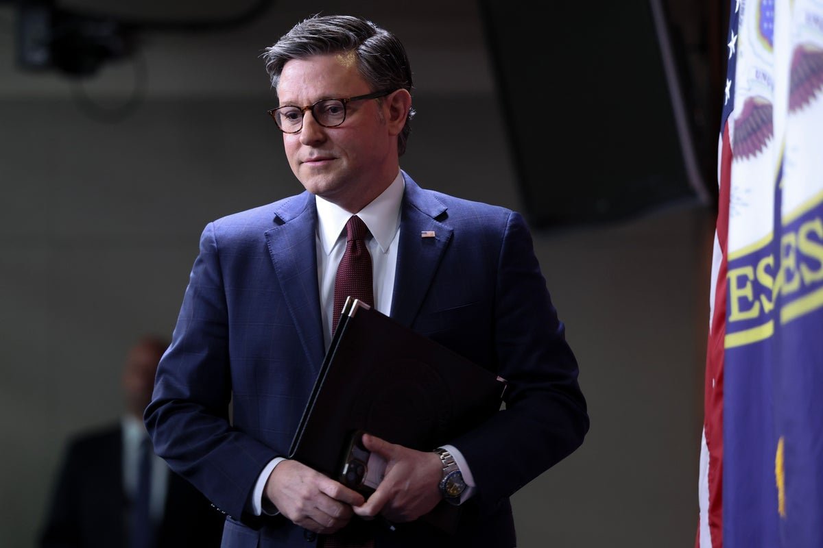 Mike Johnson speaking at a press conference, with a caption reading 'Mike Johnson's DHS bill U-Turn Sparks Fury Among Allies', with a background colour of blue, symbolising trust and stability, which has been lost due to his behaviour, and a picture of the US flag, representing the country's political landscape, with the primary keyword 'DHS bill' featured prominently