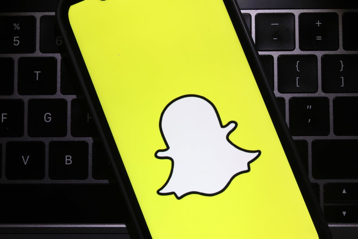 A person holding a smartphone with the Snapchat app open, with a red flag indicating a decline in the company's financial performance, as the primary keyword, Snapchat, is used naturally in this descriptive alternative text