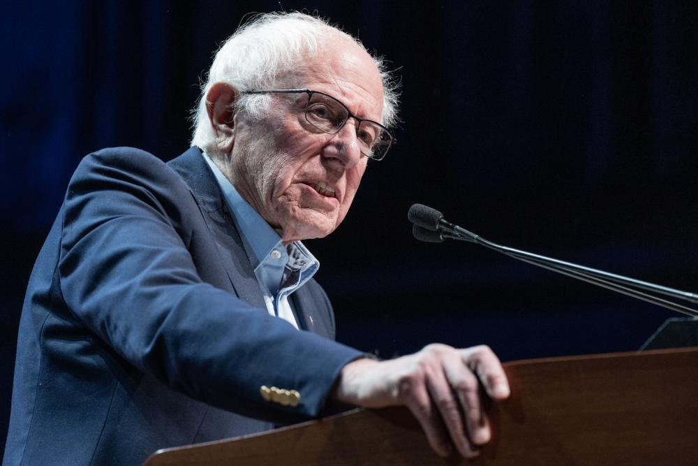 US Senator Bernie Sanders speaking in the Senate, with a backdrop of Israeli and American flags, highlighting the complex relationship between the two nations and the ongoing debate over US arms sales to Israel