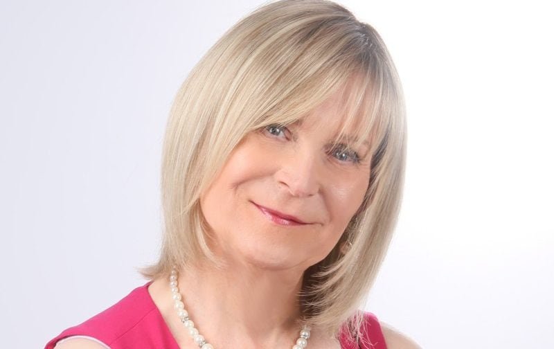 A trans woman speaking at an endometriosis awareness event, with a crowd of people in the background, highlighting the importance of diversity and inclusion in the charity sector, with a focus on endometriosis awareness and support