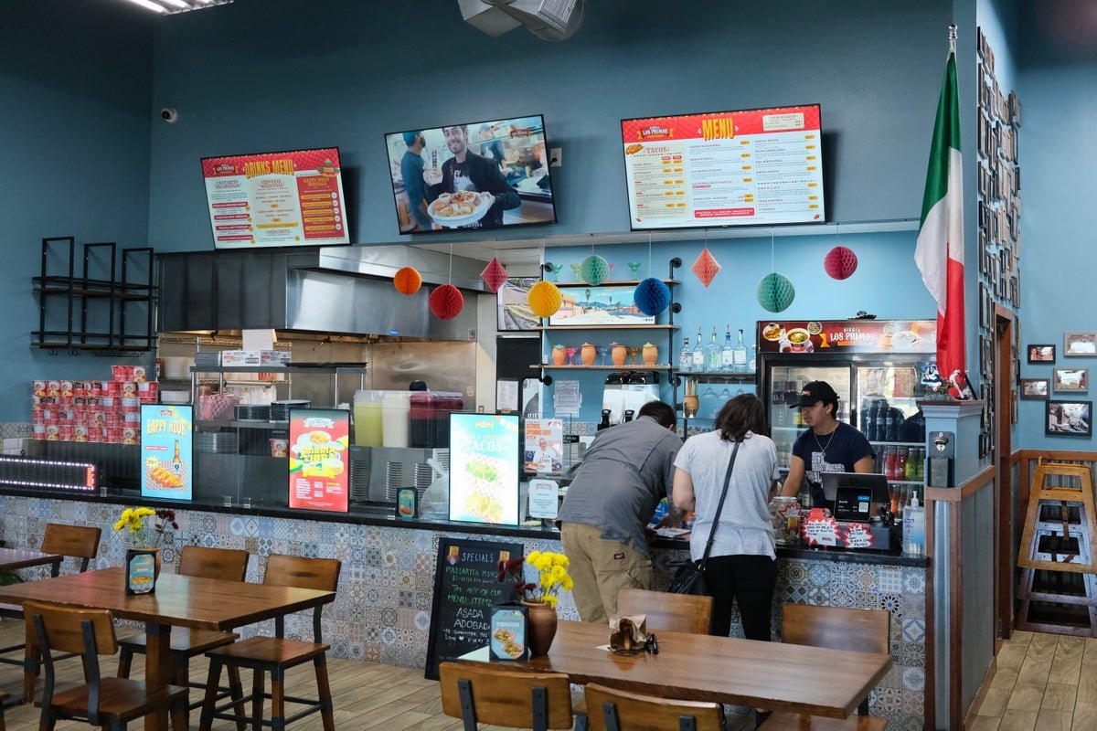 A deserted restaurant kitchen with a 'help wanted' sign on the door, highlighting the shortage of skilled food service workers due to deportation