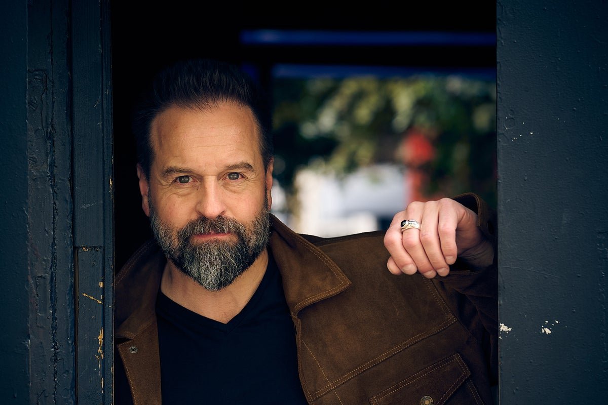 Alfie Boe, a British tenor, sits in a dimly lit room, looking introspective, with a subtle smile, as he reflects on his journey to self-forgiveness, with a warm colour palette and soft lighting, conveying a sense of hope and renewal, with the primary keyword self-forgiveness naturally included