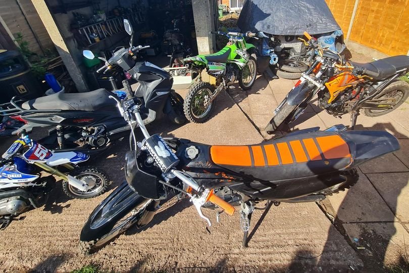 A row of recovered stolen motorbikes in Tamworth, with police officers in the background, highlighting the successful operation and the importance of community policing in preventing motorbike theft
