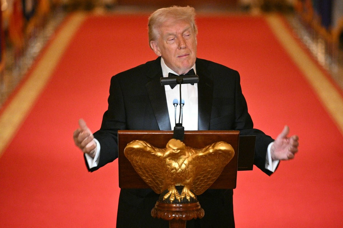 Donald Trump smiling and waving at the White House Correspondents' Dinner, surrounded by journalists and politicians, with a mixture of curiosity and scrutiny on their faces, as they analyse his every move and behaviour