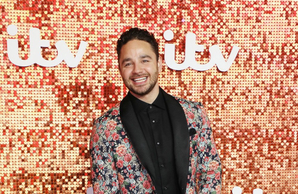 Adam Thomas, the winner of I'm a Celebrity All Stars, standing in the Australian jungle with a crown on his head, surrounded by cheering fans and a colourful background, with a mix of excitement and relief on his face, highlighting his journey to become the King of the Jungle