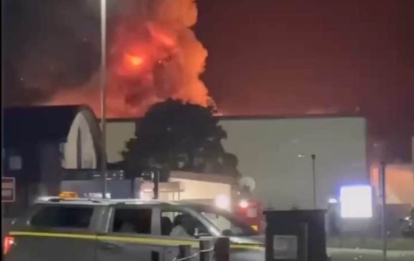 Aerial view of a US airbase with a large fire burning in the background, with firefighters and emergency responders working to bring the blaze under control, highlighting the potential disruption to US military operations and the importance of robust safety protocols, with the primary keyword being US airbase