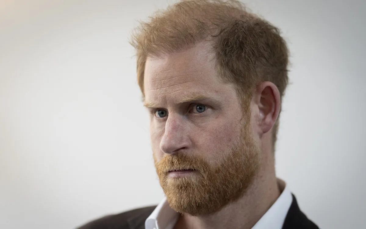 Prince Harry at a charity event, with a serious expression, surrounded by people, highlighting his charitable work and behaviour, with a focus on the defamation lawsuit against him