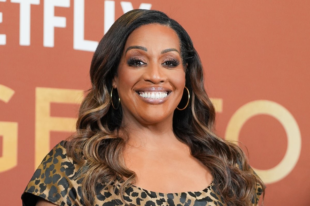 Alison Hammond smiling and holding a microphone, with a classic ITV gameshow set in the background, featuring colourful lights and excited contestants, highlighting the show's revival and her role as host