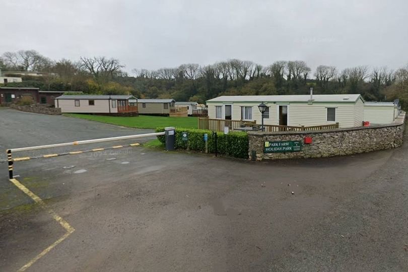 A scenic view of a Welsh holiday park with luxury lodges and glamping facilities, surrounded by lush greenery and a serene lake, highlighting the park's commitment to sustainable tourism and refusal of static caravans