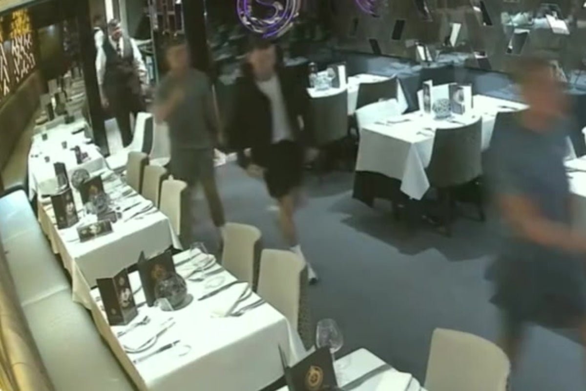 A group of people dining at a restaurant, with a baby's nappy being changed in the background, highlighting the issue of dine and dashers and their tactics, including fake emergencies and food contamination, which is a major concern for restaurant owners and customers alike, and can be considered a form of food fraud