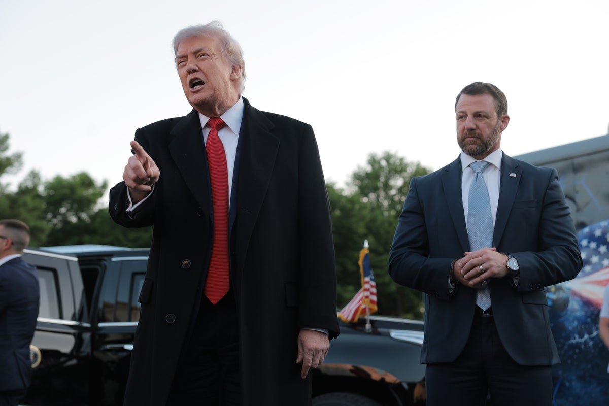 A photograph of Donald Trump standing in a grand ballroom, with a subtle hint of controversy in the background, as the primary keyword 'taxpayer funding' is naturally incorporated into the descriptive alternative text