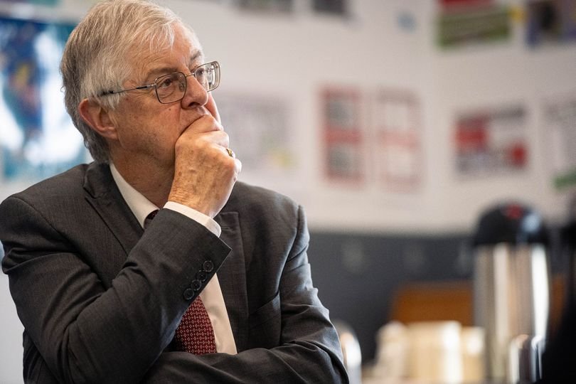 A Labour politician speaking out against the UK Government and Mark Drakeford, with a background of Welsh flags and parliament buildings, highlighting the importance of Welsh politics and government accountability