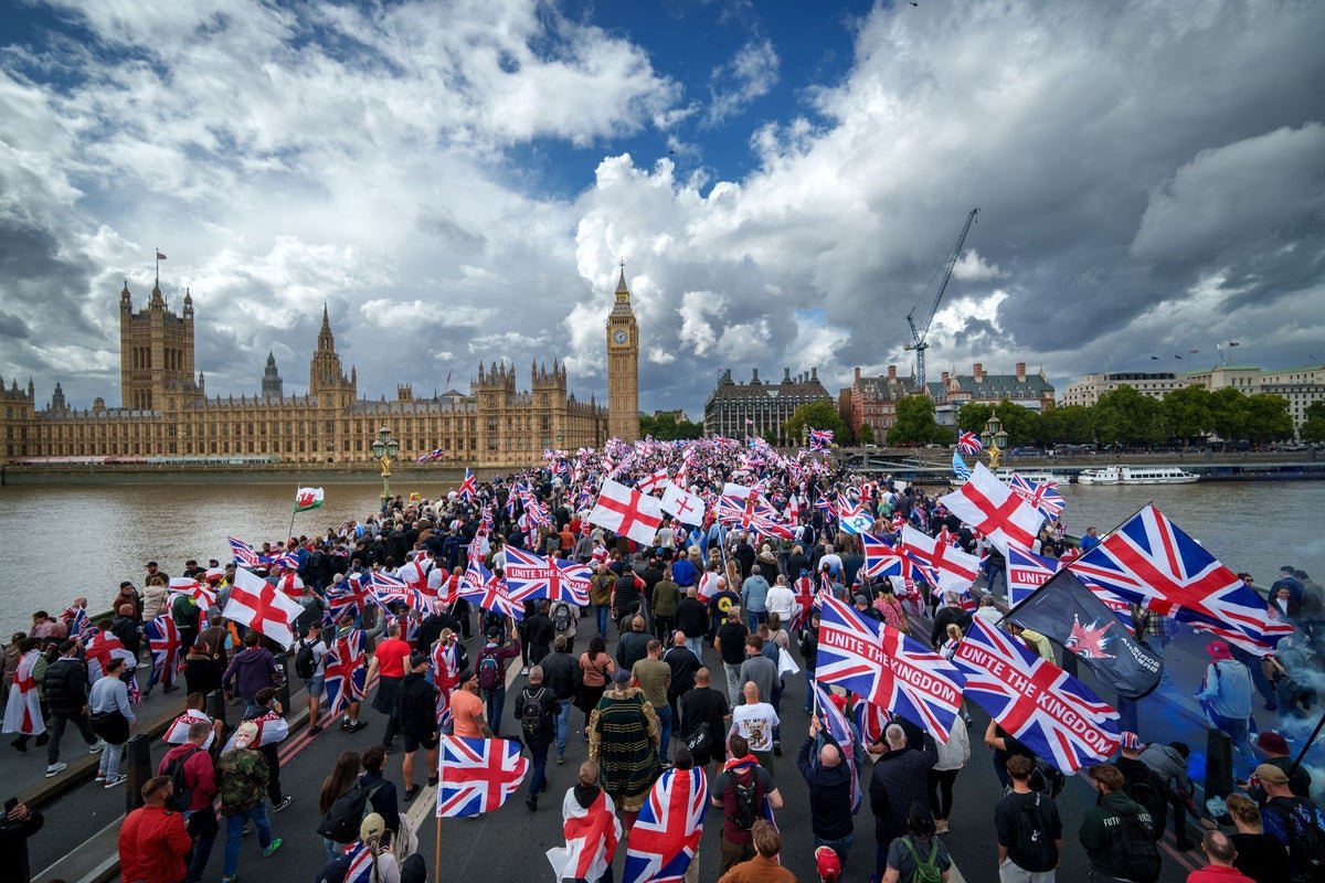 A crowd of people gathered at the Unite the Kingdom march, with a mix of faces and banners on display, highlighting the diversity and controversy surrounding the event, with a focus on Tommy Robinson and his supporters