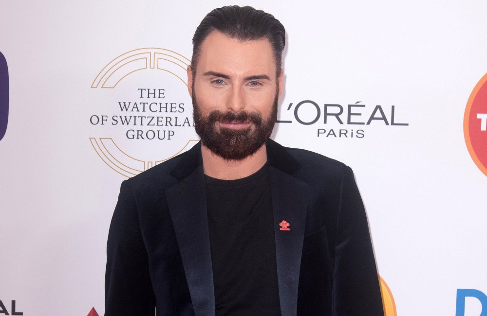 Rylan Clark, a British television personality, sparks gossip about his love life with a cryptic comment, leaving fans to analyse his behaviour and speculate about his marital status, as he poses for a photo with a mysterious smile, surrounded by a colourful background, with a hint of romance in the air