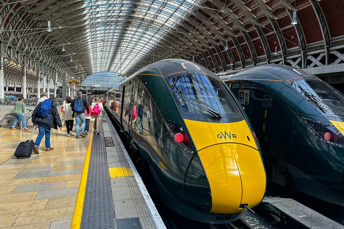 A crowded train station with passengers waiting for delayed trains, a woman checking her phone for updates on the UK rail network disruptions
