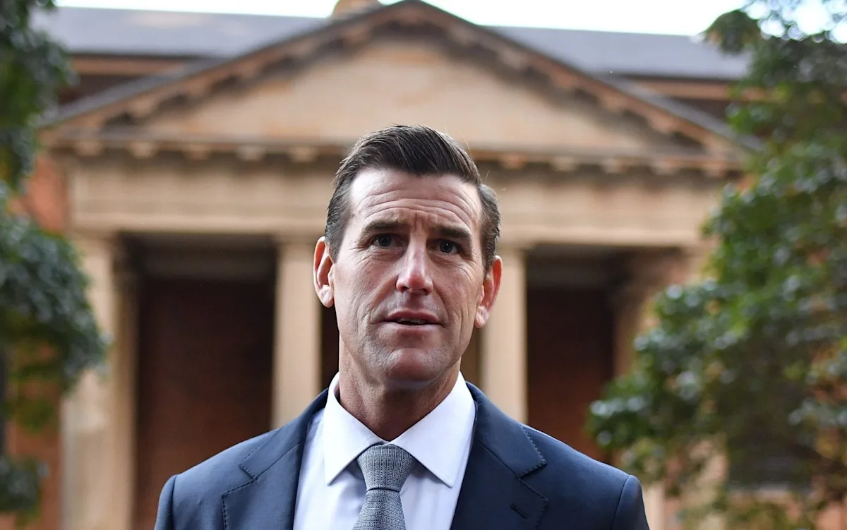 Australian soldier in combat gear, with a serious expression, surrounded by a blurred background of a war zone, highlighting the complexity and seriousness of war crimes allegations