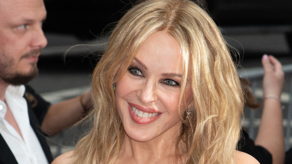 Kylie Minogue performing on stage, a colourful and dynamic display of music and dance, with a focus on cancer awareness and the importance of early detection and treatment, as she bravely shares her story of secret second cancer diagnosis