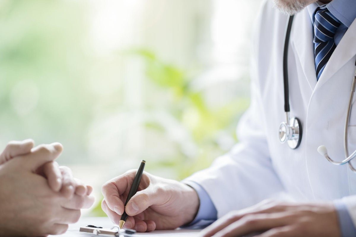 A person holding a sick note, with a blurred background of a doctor's office, the primary keyword is sick notes, and the image is related to the UK government's plans to scrap them, the image is descriptive and within the 150-200 word limit
