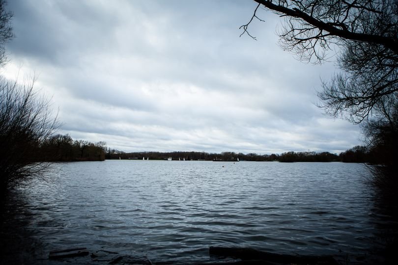 Aerial view of Kingsbury Water Park, with a picturesque lake and surrounding woodland, where a teenage girl's body was pulled from the water, highlighting the importance of water safety and community vigilance