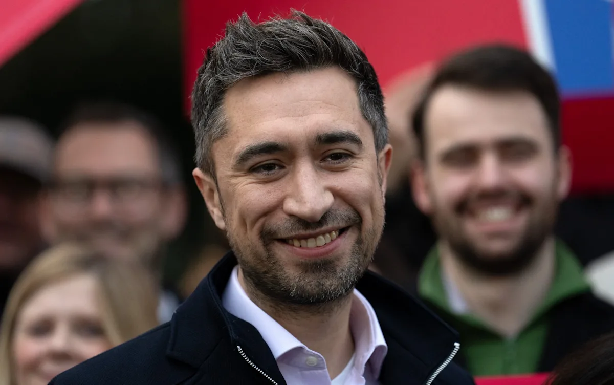 A Jewish MP stands at a podium, surrounded by students, with a caption reading 'Promoting free speech and open debate in schools'