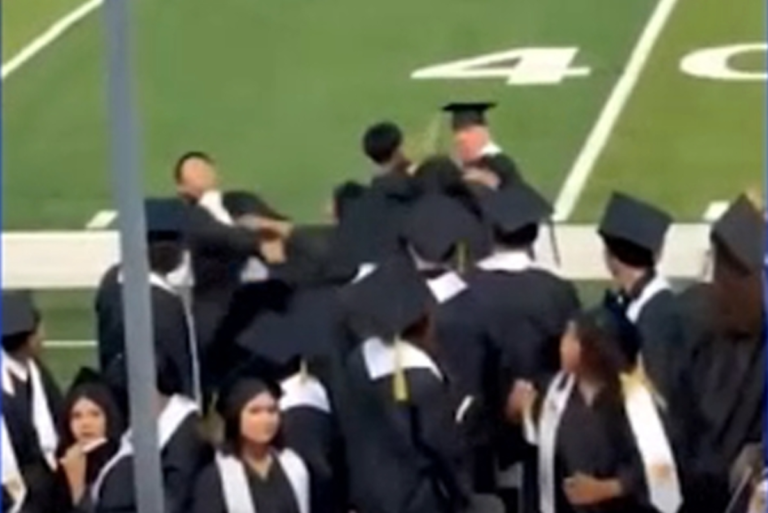 A group of students in caps and gowns engaging in a wild brawl as names are being called at their graduation ceremony, with a focus on the graduation brawl and its impact on the students involved