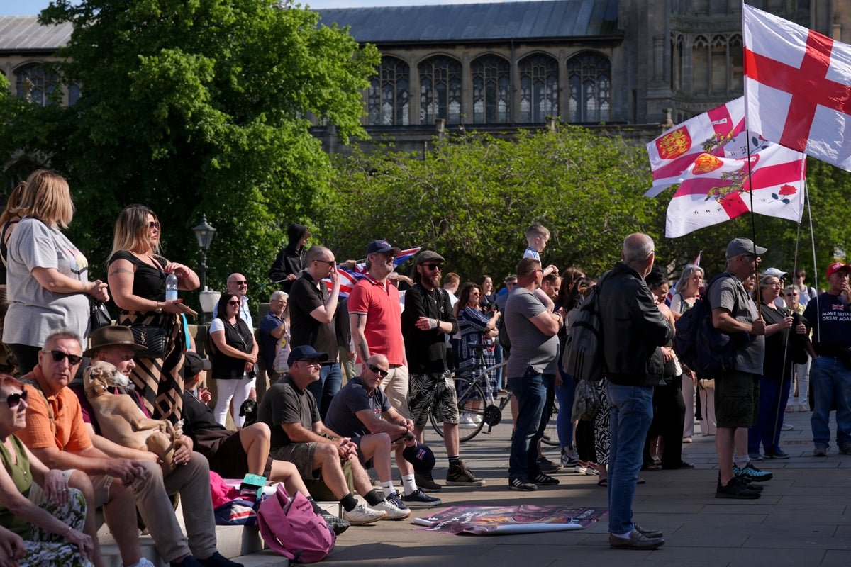 A crowd of protesters holding signs and banners in Norfolk, with a focus on community safety and immigration concerns, highlighting the need for effective solutions to the refugee crisis