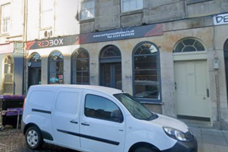 A photo of the exterior of the beloved Edinburgh noodle bar, with a sign reading 'closed' and a crowd of people outside, showcasing the bar's unique colour scheme and decor, with a focus on the primary keyword 'Edinburgh noodle bar'