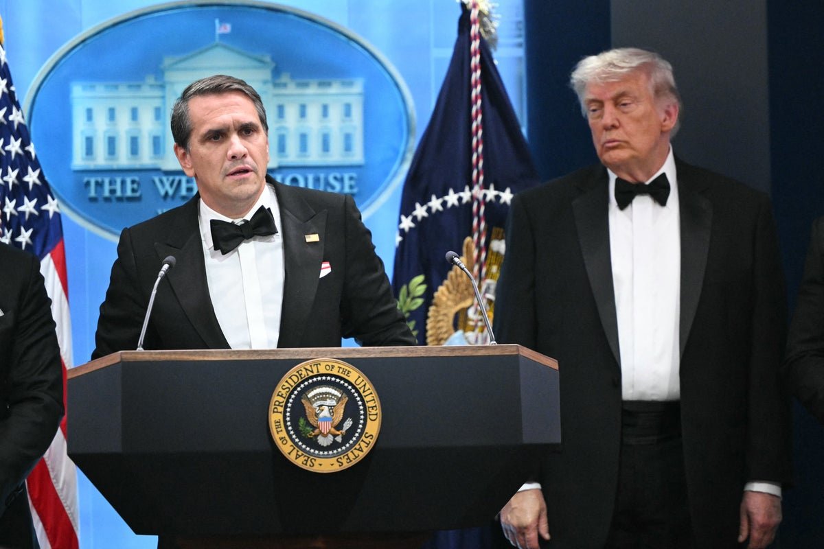 Acting AG Todd Blanche speaking at a press conference about Trump's potential prison sentence, with a serious expression and a backdrop of American flags, analysing the behaviour of the former President