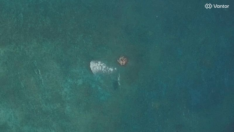 A satellite image of the South China Sea, showing a suspected structure at a disputed atoll, with the colour of the water and the movement of ships clearly visible, highlighting the primary keyword of South China Sea