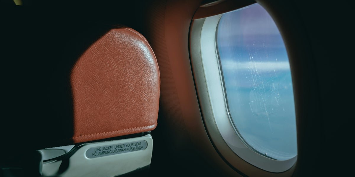 Aircraft window blinds open during takeoff, allowing natural light to illuminate the cabin and providing an unobstructed view of the surrounding environment, with a clear blue sky and fluffy white clouds in the background, showcasing the primary keyword of aircraft window blinds