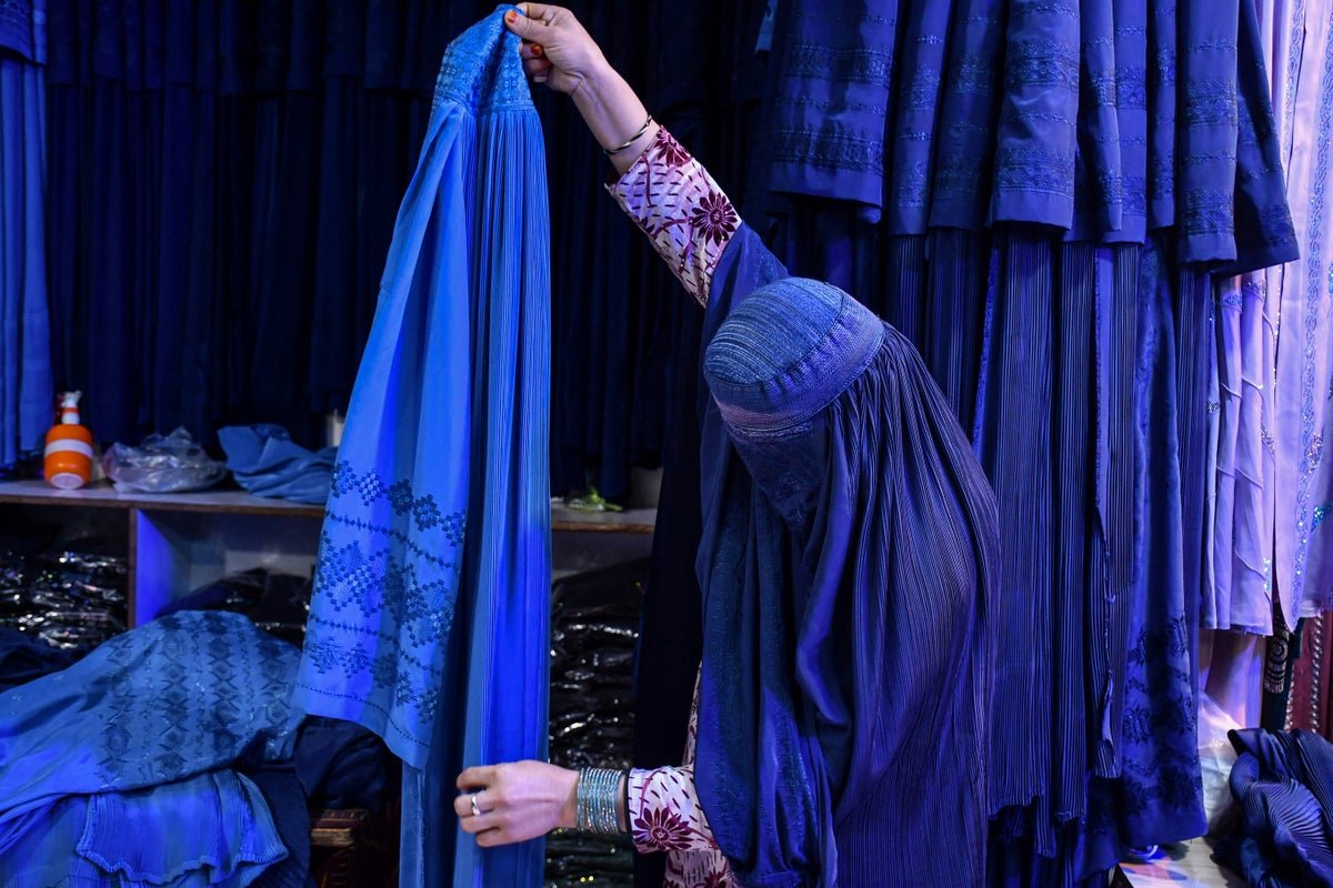 A woman in a burqa walks down a street in Kabul, Afghanistan, as the Taliban enforces its strict dress code, sparking concerns about women's rights and human rights violations