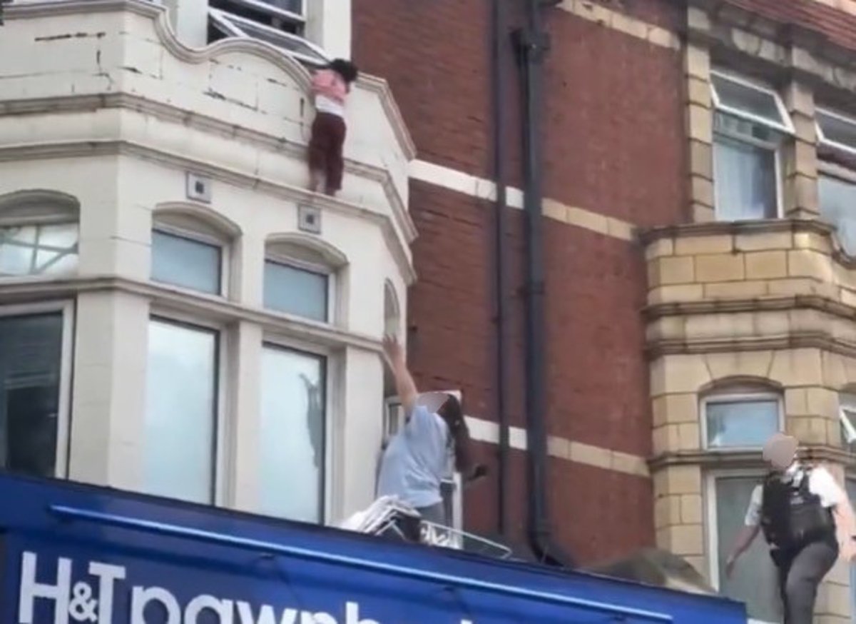 A child clinging to a window ledge above a high street shop in London, as firefighters and paramedics carry out a dramatic rescue operation, highlighting the importance of child safety and secure windows
