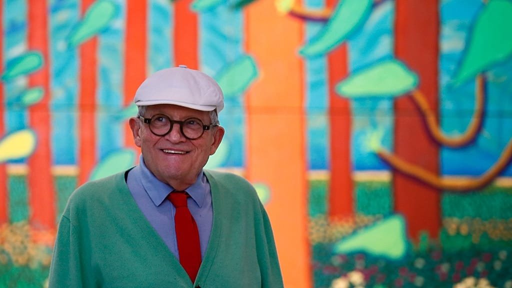 David Hockney sitting by a pool, surrounded by his vibrant paintings, a true reflection of his innovative and creative personality, with a mix of bold colours and geometric shapes, a hallmark of his unique style and behaviour as an artist
