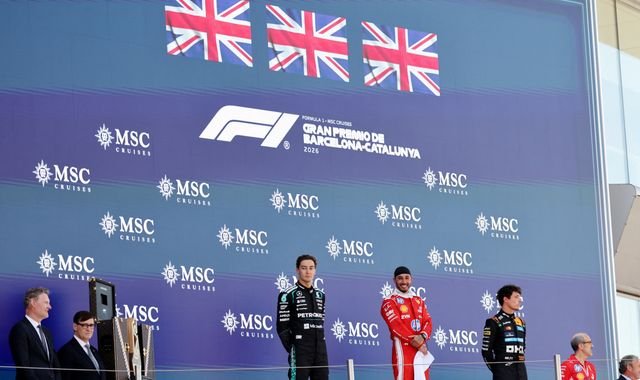 The all-British podium at the Barcelona-Catalunya Grand Prix, featuring Hamilton, Russell, and Norris, with a crowd of cheering fans in the background, capturing the electric atmosphere and colour of the event, with the primary keyword of Barcelona-Catalunya Grand Prix