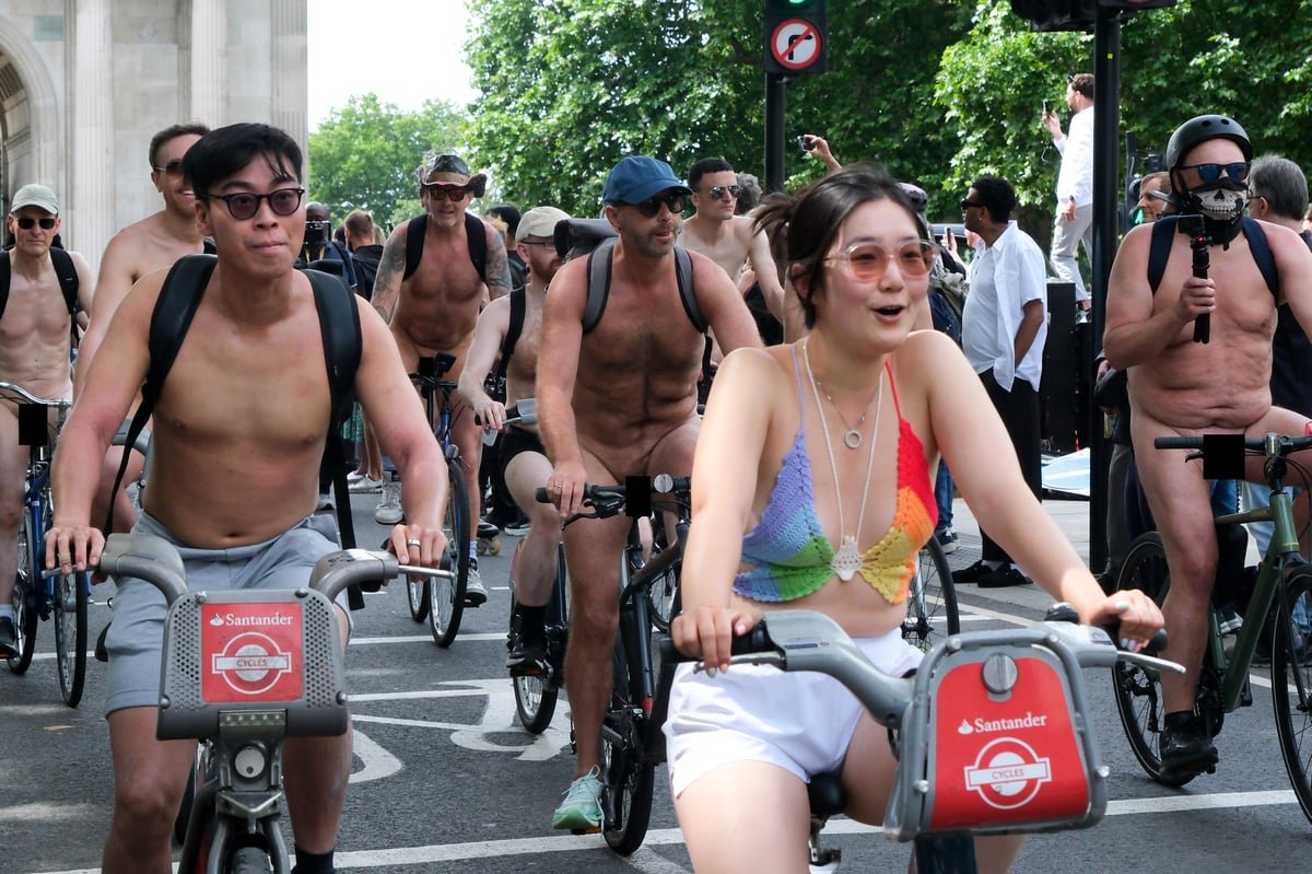 A group of cyclists participating in the World Naked Bike Ride in central London, with a backdrop of the city's iconic landmarks and a sea of colourful costumes and decorations, highlighting the primary keyword of World Naked Bike Ride