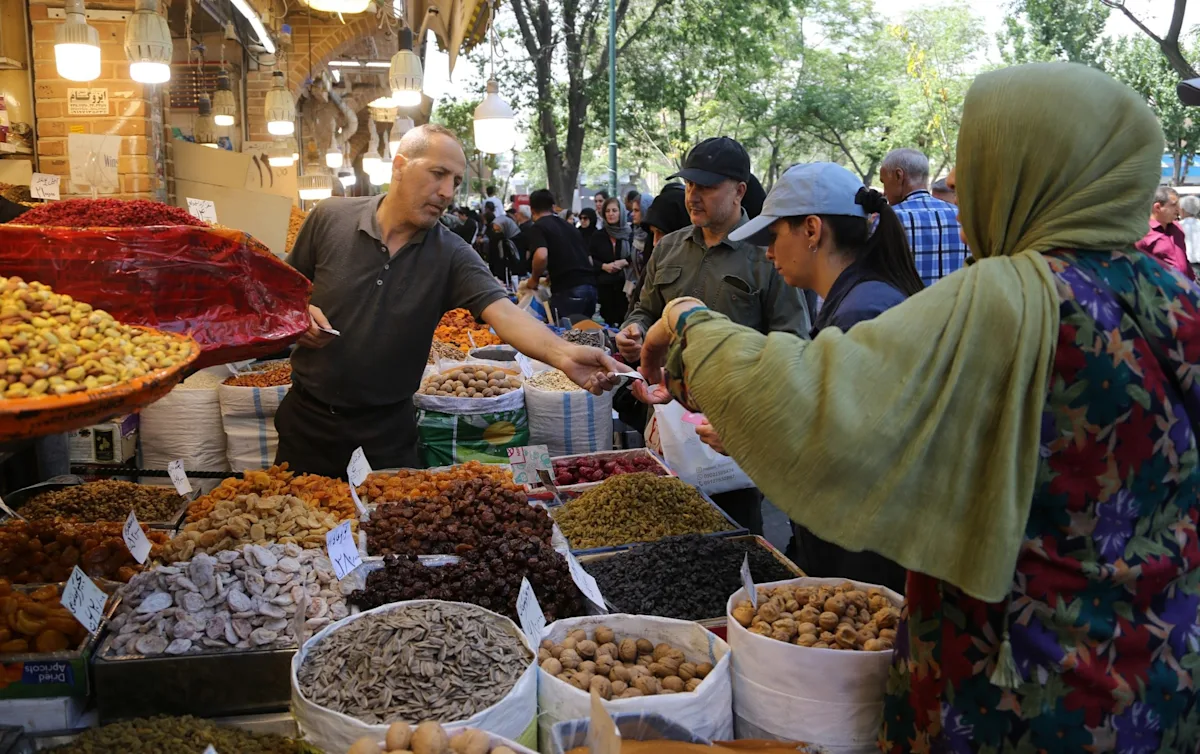 A person in Iran struggling to buy basic necessities due to the high cost of living caused by the US economic sanctions and blockade, with a blurred background of a market scene, highlighting the primary keyword of Iran cost of living.