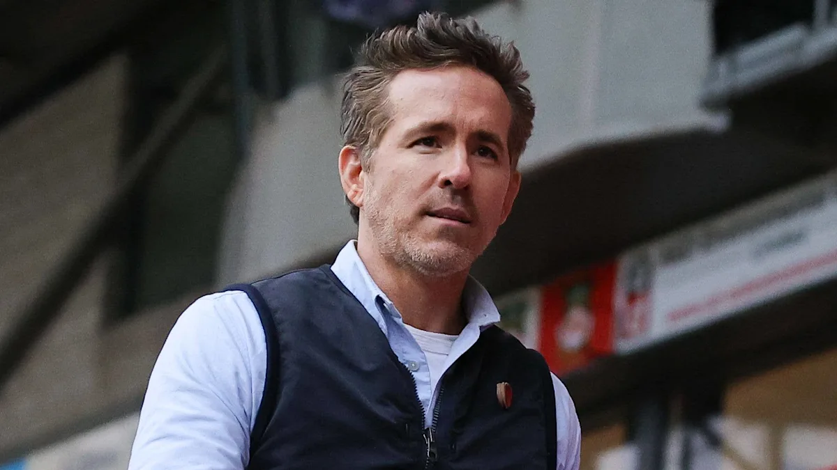 Ryan Reynolds looking concerned and stressed, with a blurred background of legal documents and courtrooms, highlighting the impact of ongoing legal battles on his mental health and wellbeing