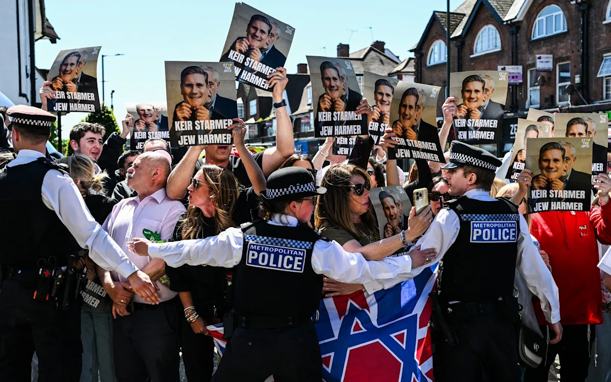 Keir Starmer speaking at a Labour party conference, with a backdrop of Labour party flags and a crowd of supporters, the primary keyword anti-Semitism is a major concern for the Labour party
