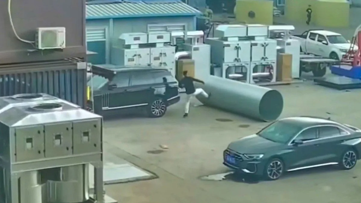 A man rushes to save a car from a runaway steel roll, which is heading straight for the vehicle, posing a significant threat to the car's safety, with the primary keyword being runaway steel roll