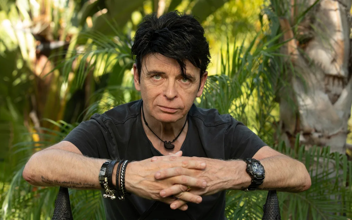 Gary Numan performing live on stage, surrounded by synthesizers and guitars, with a backdrop of colourful lights, showcasing his unique blend of synth-pop and rock music, with a focus on his primary keyword, Gary Numan