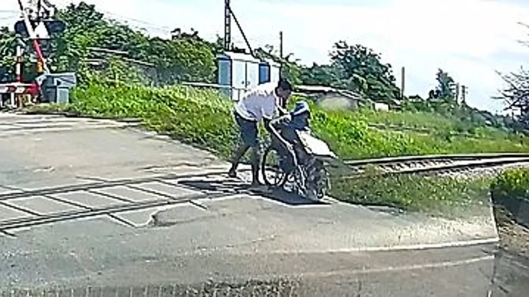 A photo of a wheelchair vendor stuck on a railway crossing, with a driver rushing to his aid, highlighting the importance of railway crossing safety and disability accessibility
