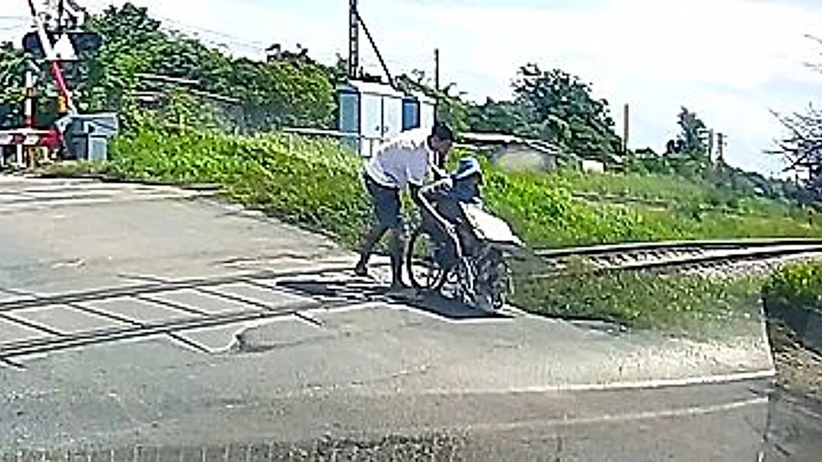 A photo of a wheelchair vendor stuck on a railway crossing, with a driver rushing to his aid, highlighting the importance of railway crossing safety and disability accessibility