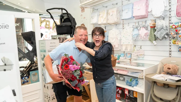 A former delivery driver smiling and handing out gifts to their former colleagues, spreading joy and kindness in the workplace, after a life-changing lottery win