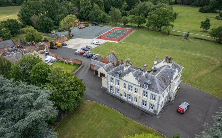 Travellers camping near a historic estate, with caravans and tents scattered across the landscape, highlighting the issue of illegal camping and its impact on the environment and local community, with a focus on the primary keyword of travellers
