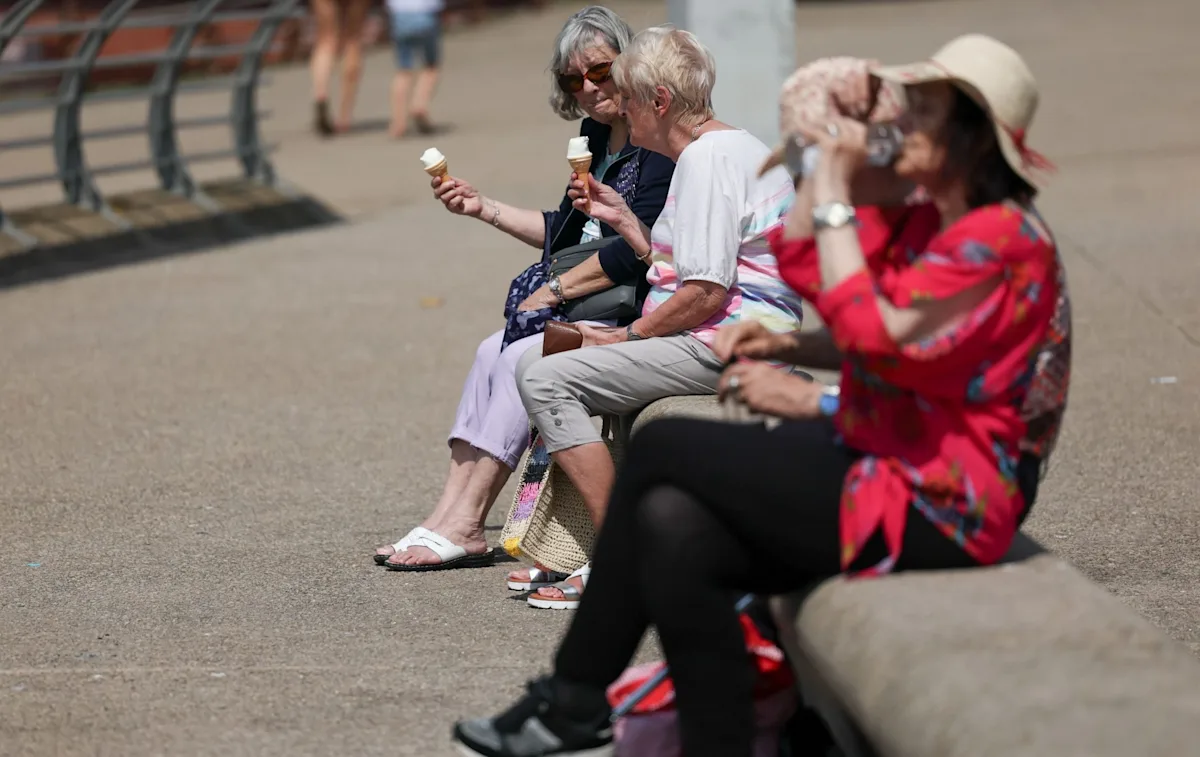 A descriptive image of a sunny day in the UK, with people enjoying the warm weather in a park, with a temperature gauge in the background showing high temperatures, highlighting the UK heatwave